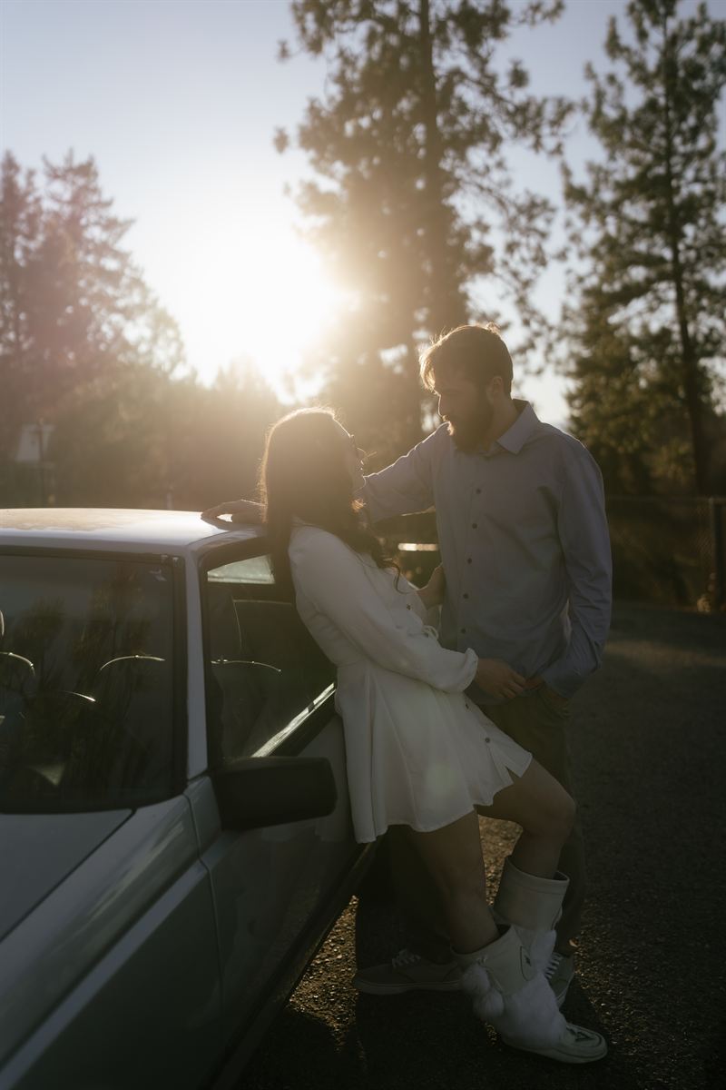 Couple leaning against a truck on a forest road at sunset, ponderosa pines catching the last light