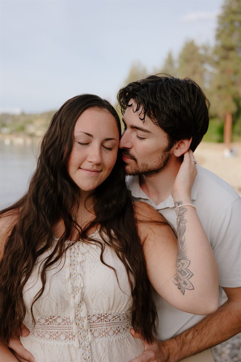 He kisses her temple on a beach beside Okanagan Lake, her eyes closed