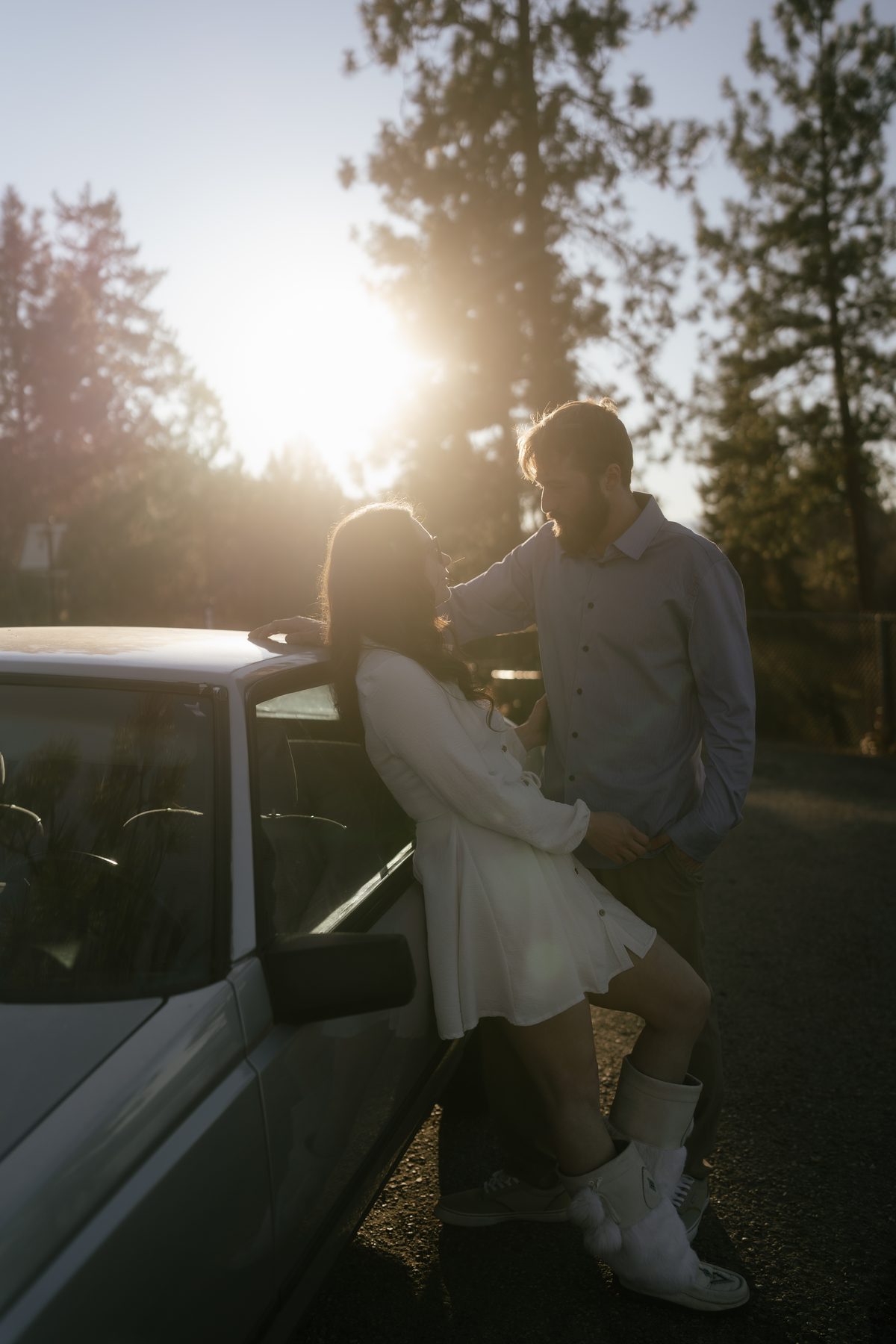 Couple leaning against a truck on a forest road at sunset, ponderosa pines catching the last light