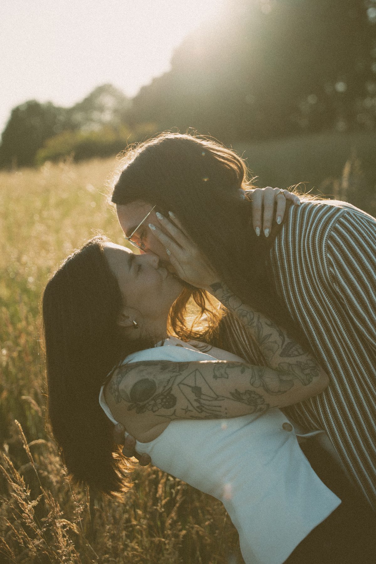 He leans down to kiss her in a golden meadow, her hand at his cheek