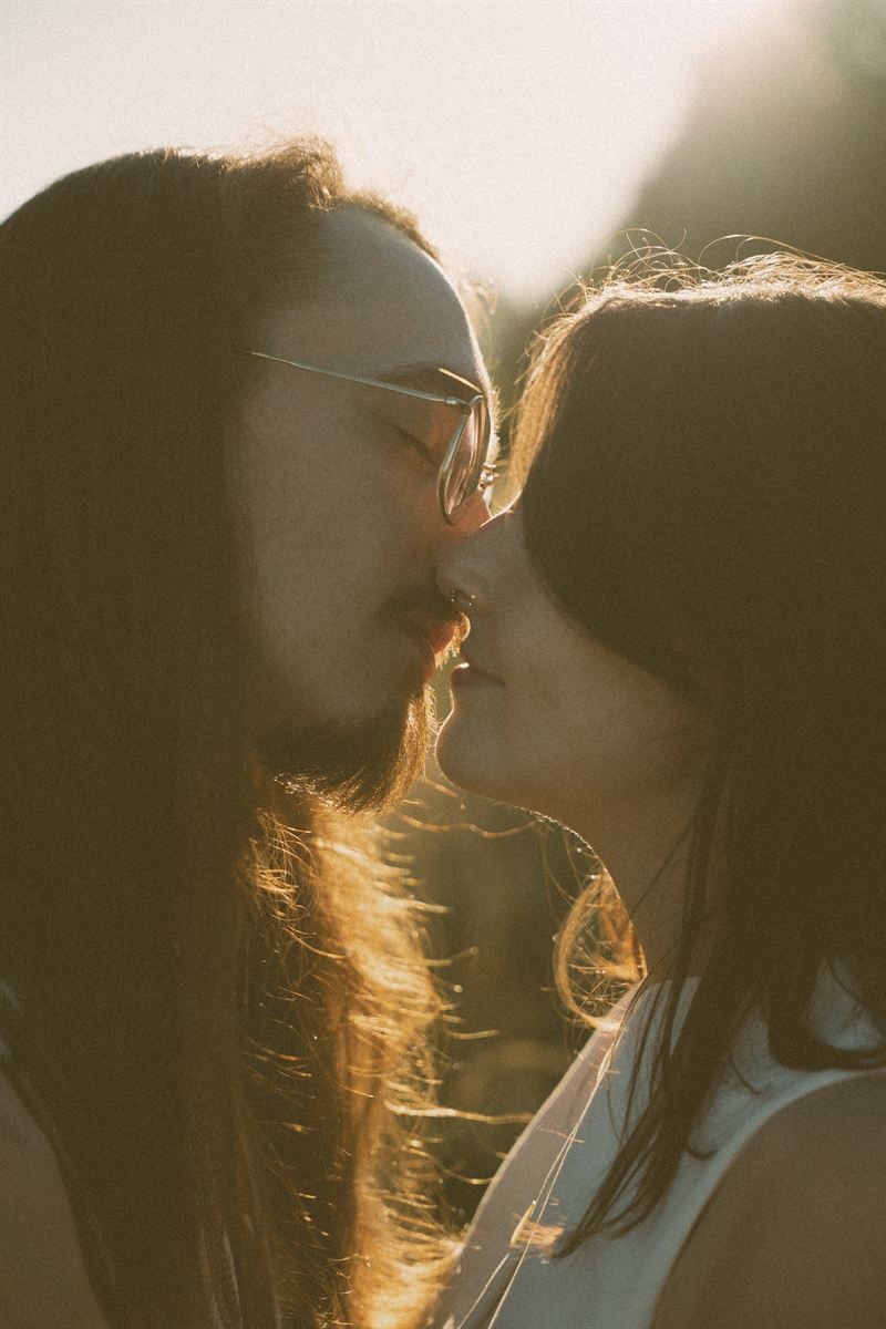 Backlit close-up of a couple about to kiss, sunlight catching in their hair