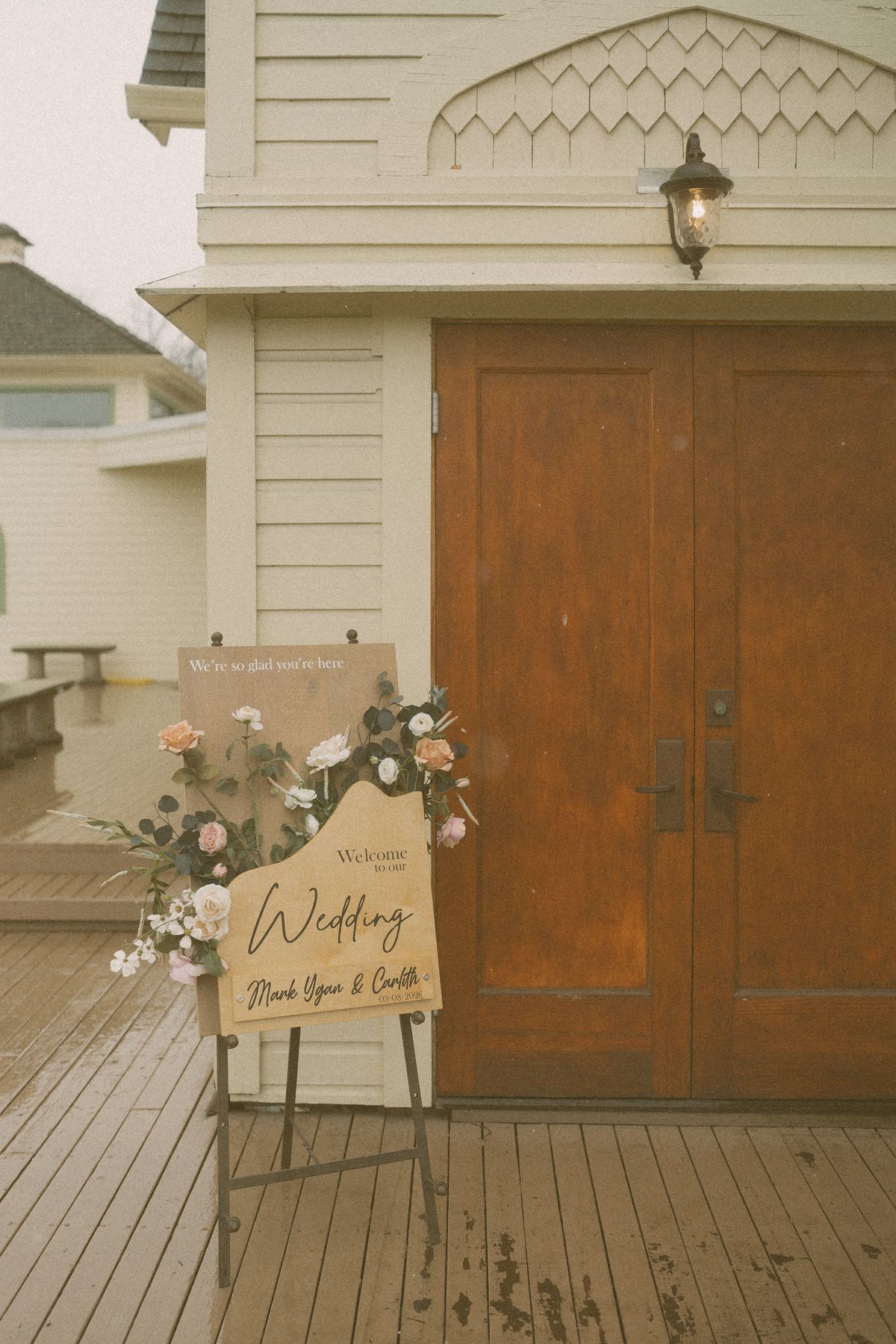 Welcome sign and florals at the church's wooden doors
