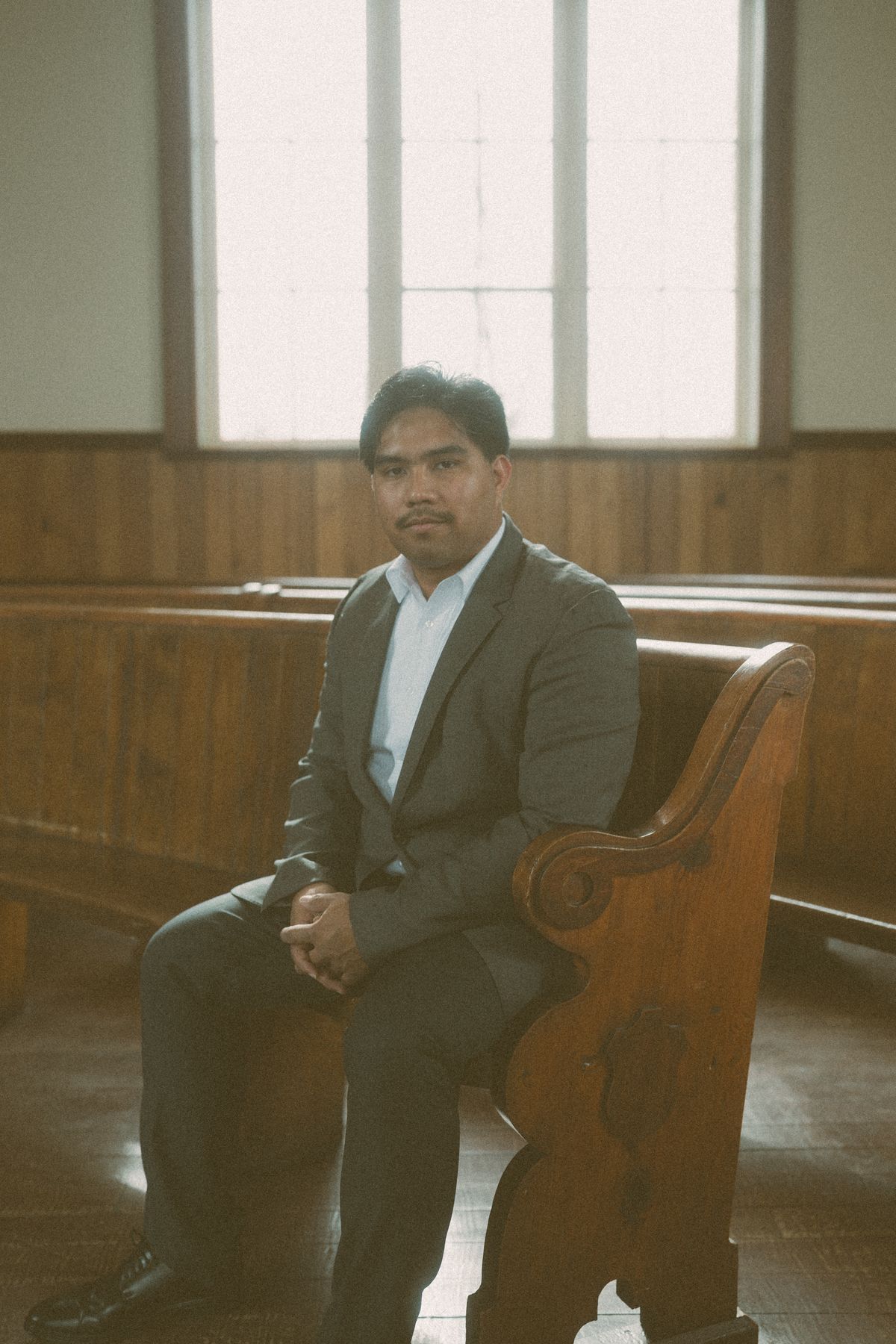 Groom waiting in a wooden pew inside Benvoulin Heritage Church