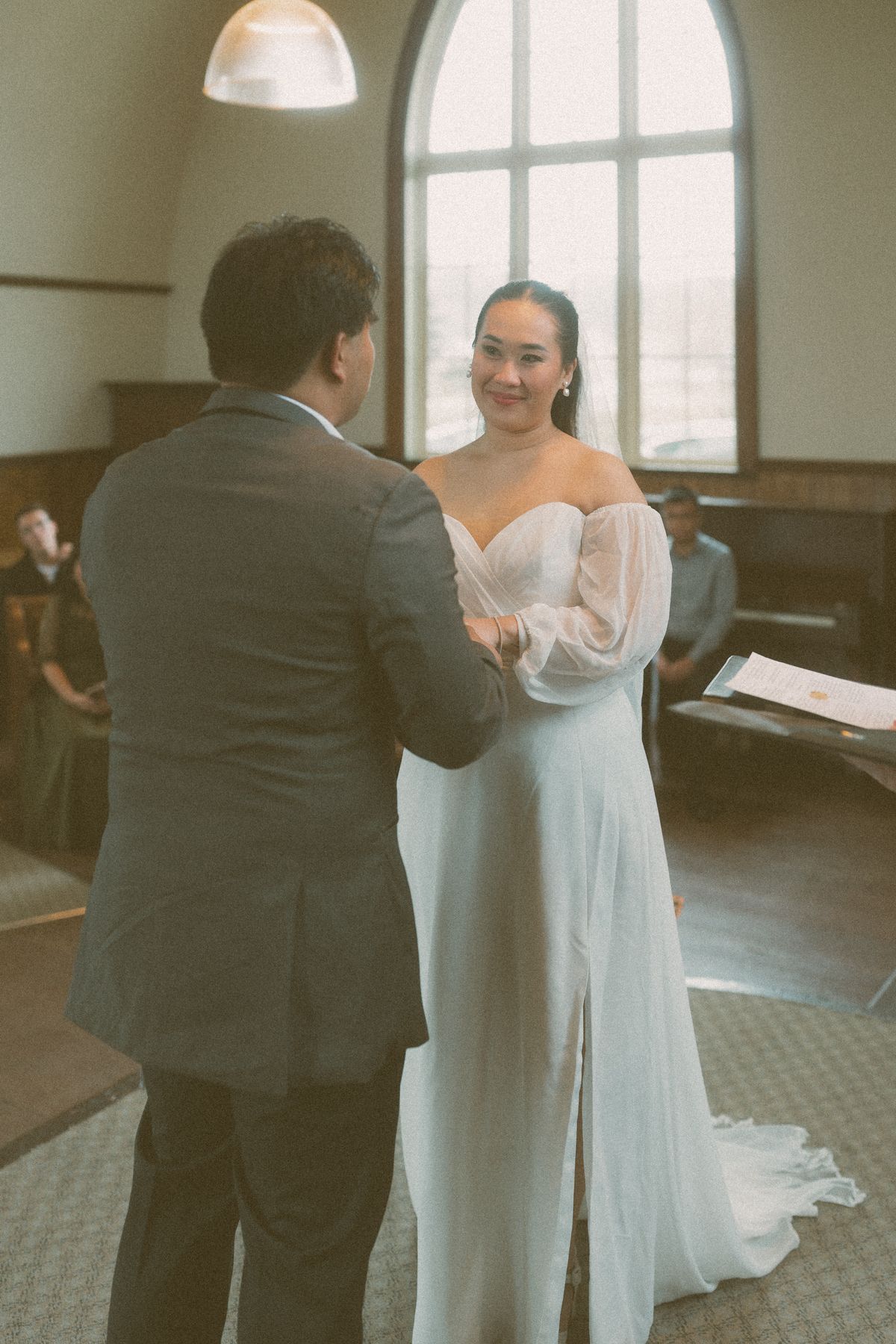 The couple holding hands together by the piano inside the church
