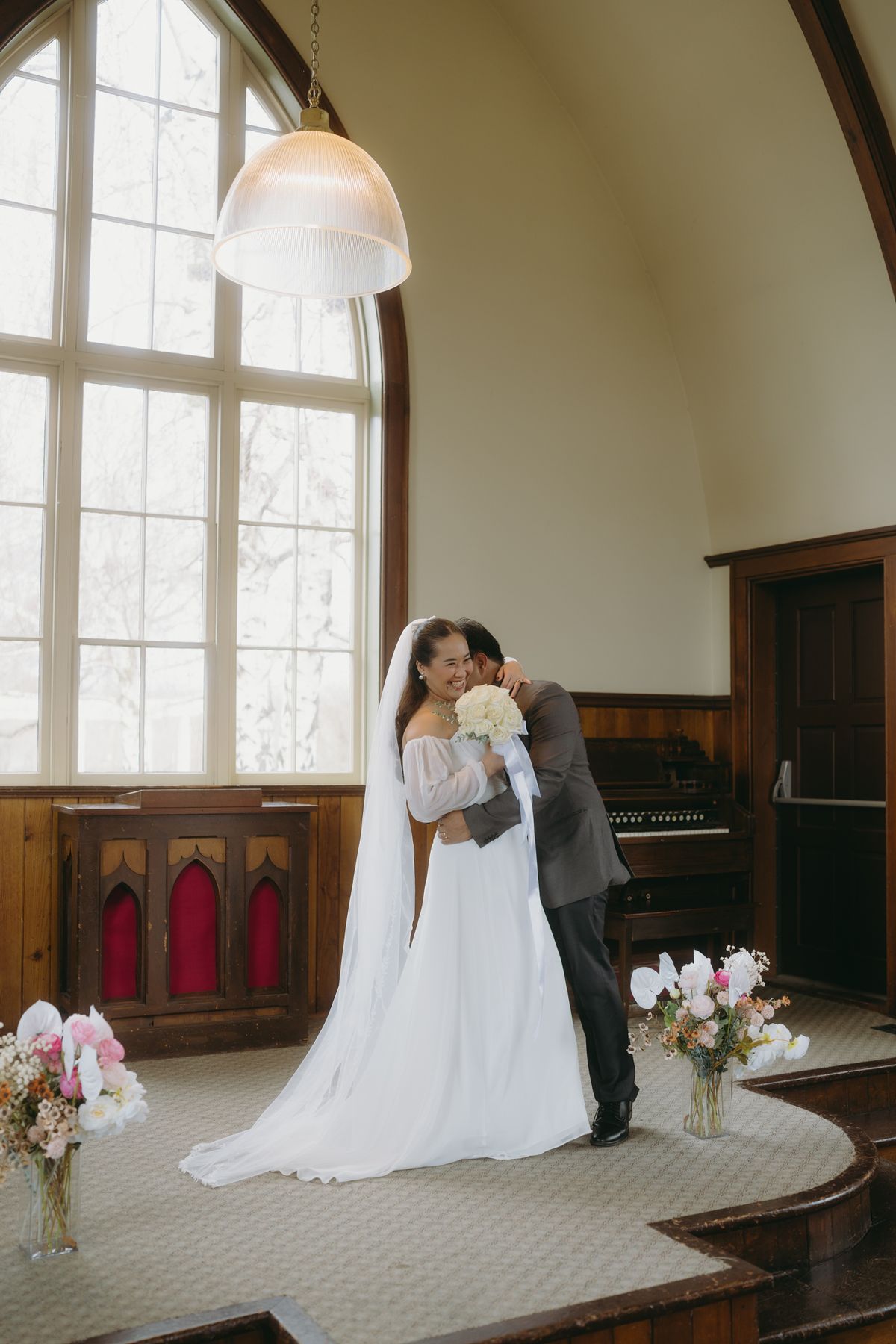 Groom holding the bride close, her train sweeping across the chapel floor