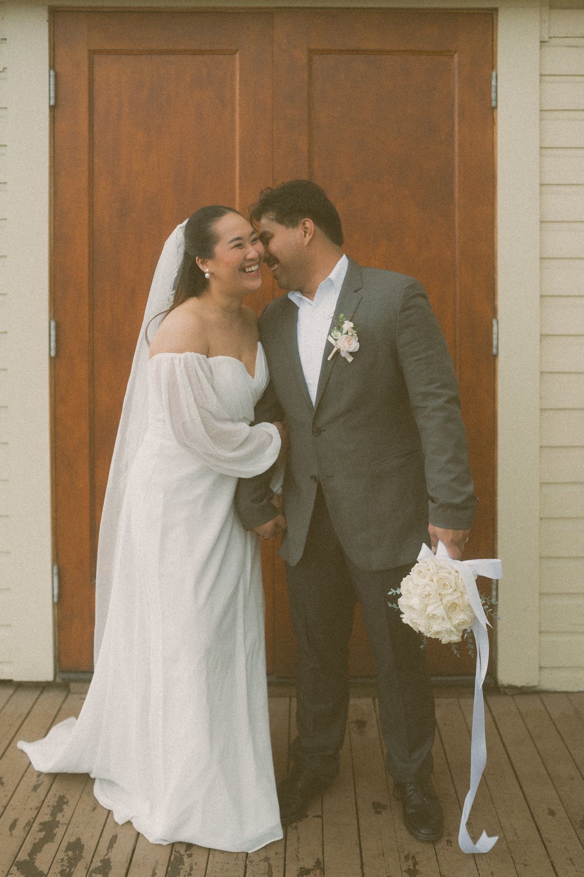 Groom kissing the bride's cheek by the wooden doors