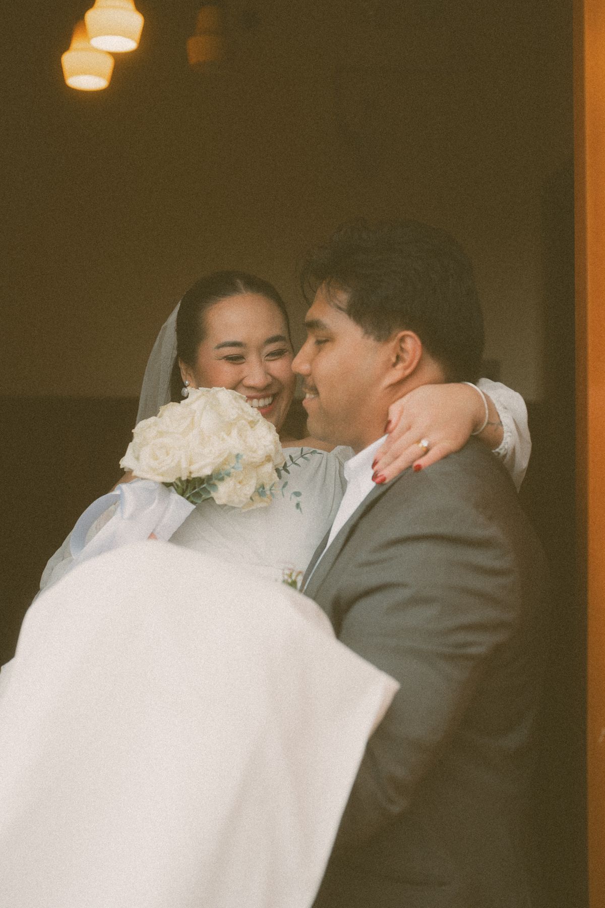 Groom kissing the bride, her veil wrapped around them