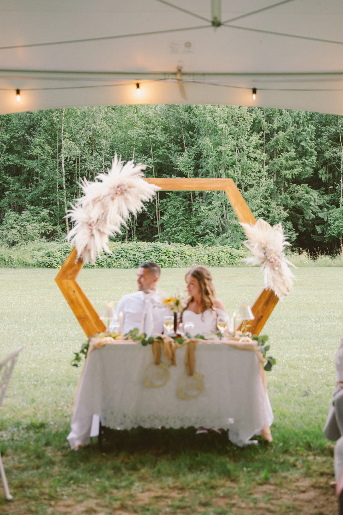 Kendra and Rory at their sweetheart table beneath the pampas arch and string lights