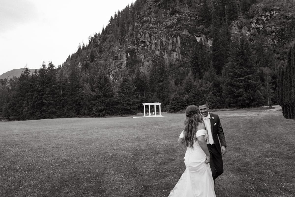 Black and white of Kendra and Rory walking the meadow below the rock face