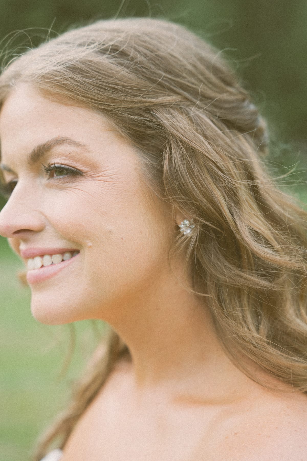 Close profile portrait of Kendra smiling, her earring and hair catching the light