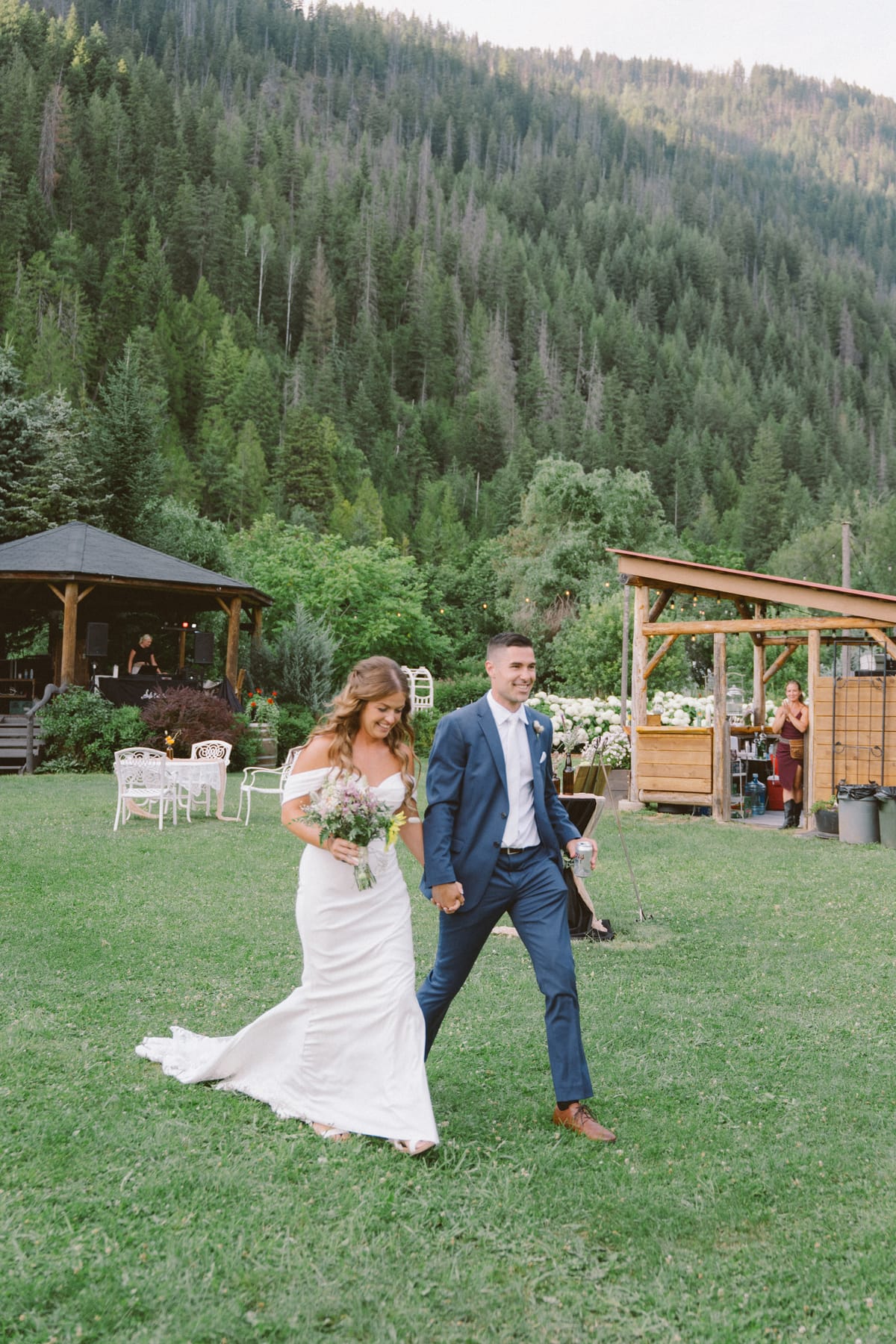 Kendra and Rory crossing the reception lawn past the gazebo and bar pavilion