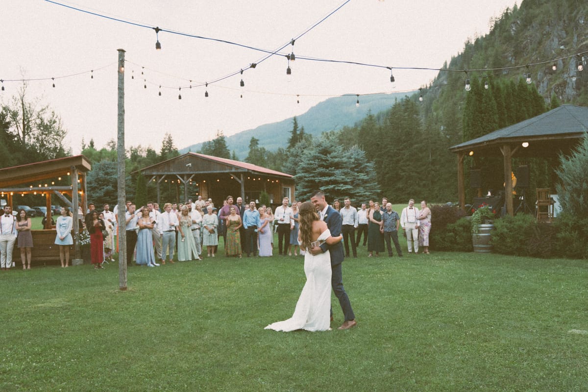 Kendra and Rory's first dance on the lawn as guests gather round under string lights