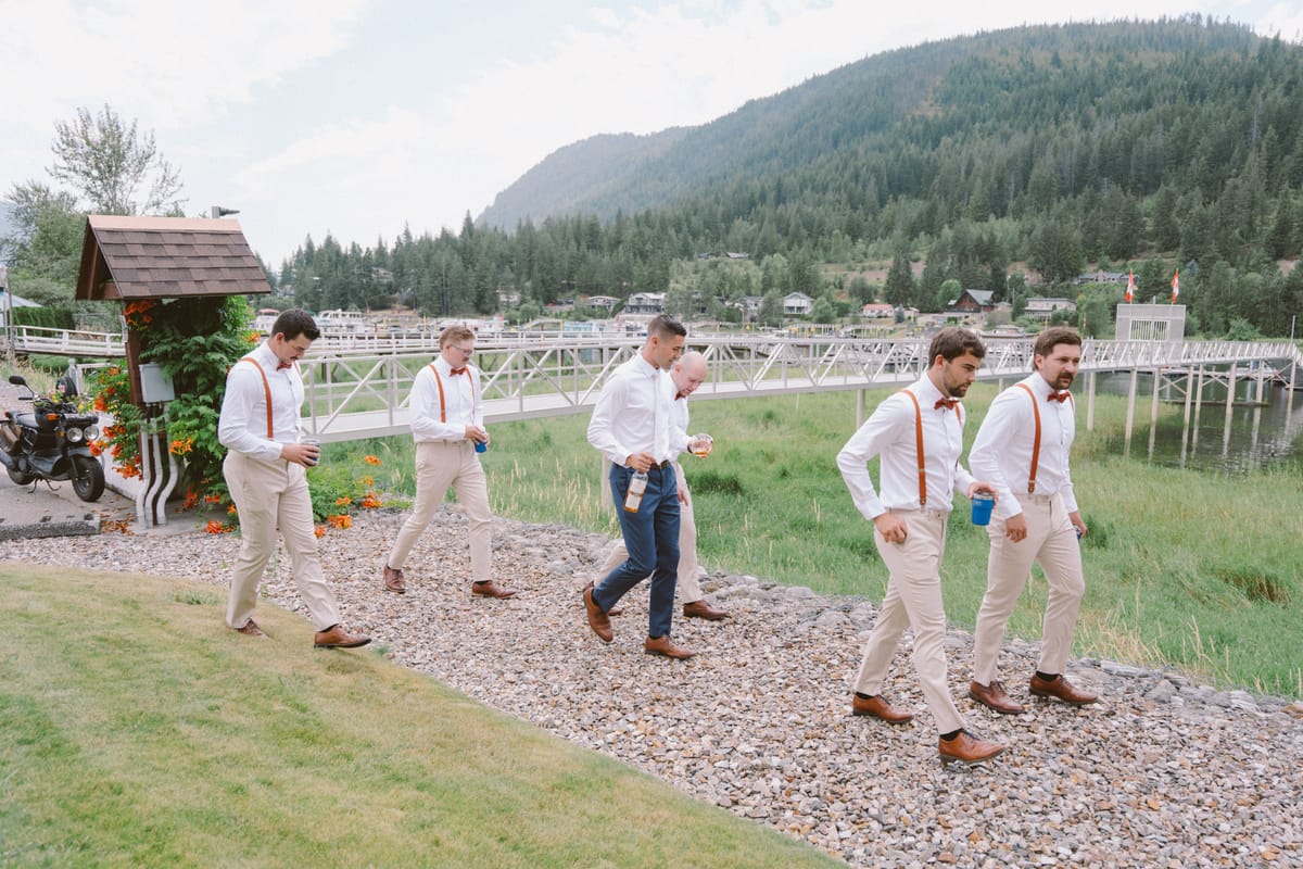 The groomsmen walking down to the water with their drinks at Cambie Country Gardens