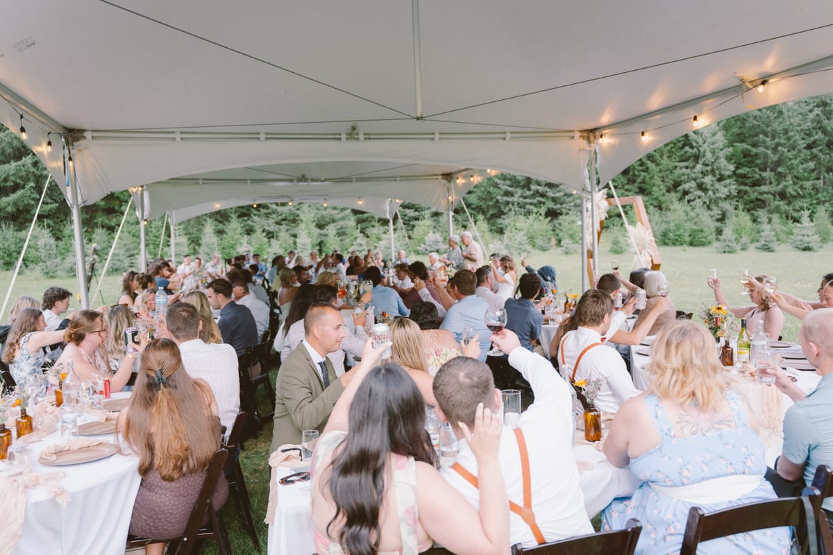 Guests raising a toast at the long tables under the marquee tent