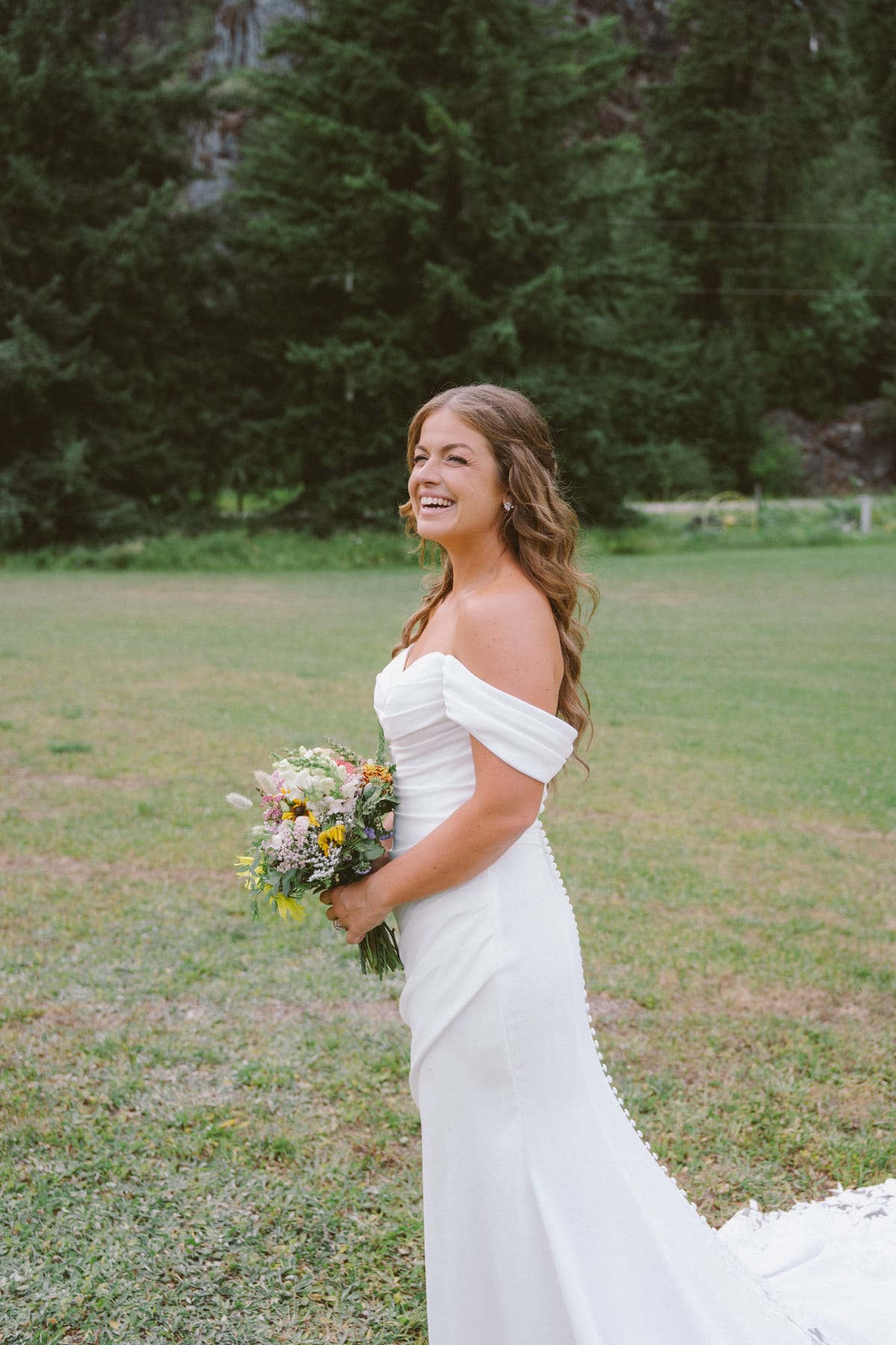 Portrait of Kendra laughing in her off-shoulder gown with her wildflower bouquet