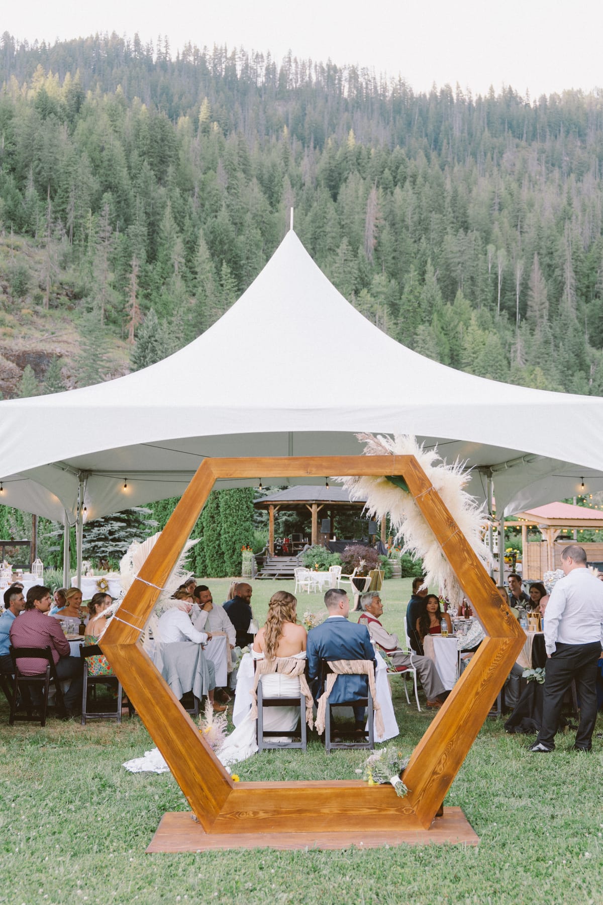 The couple's sweetheart table under the marquee seen through the hexagonal arch