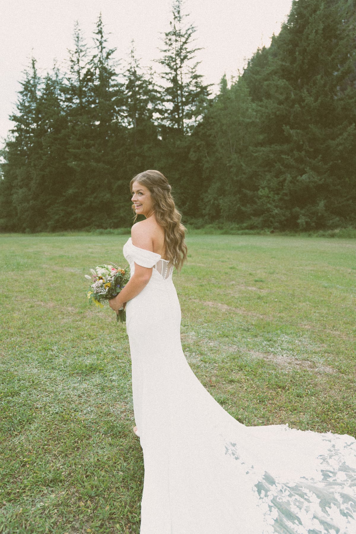 Kendra looking back over her shoulder, her long train trailing across the meadow
