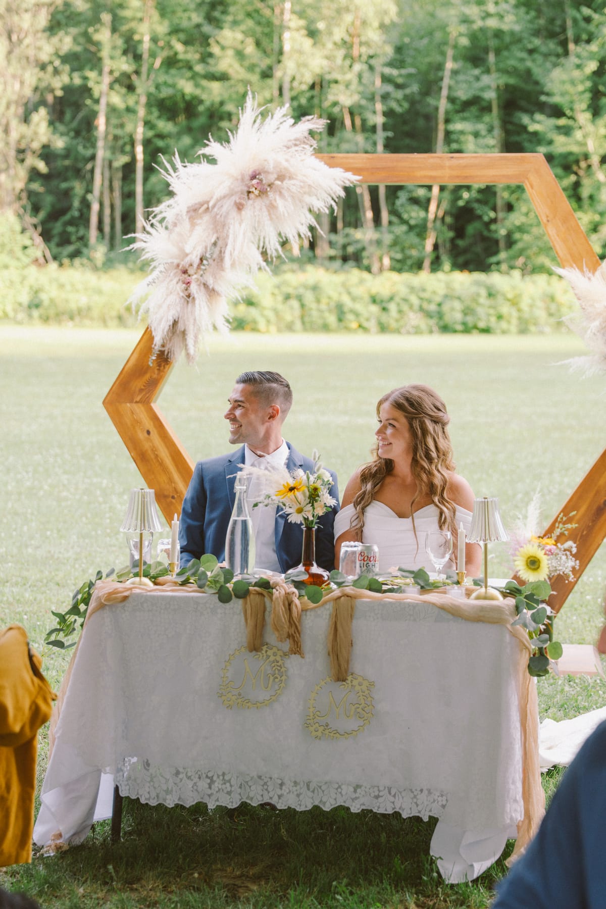 Kendra and Rory at their sweetheart table with the pampas arch and eucalyptus runner