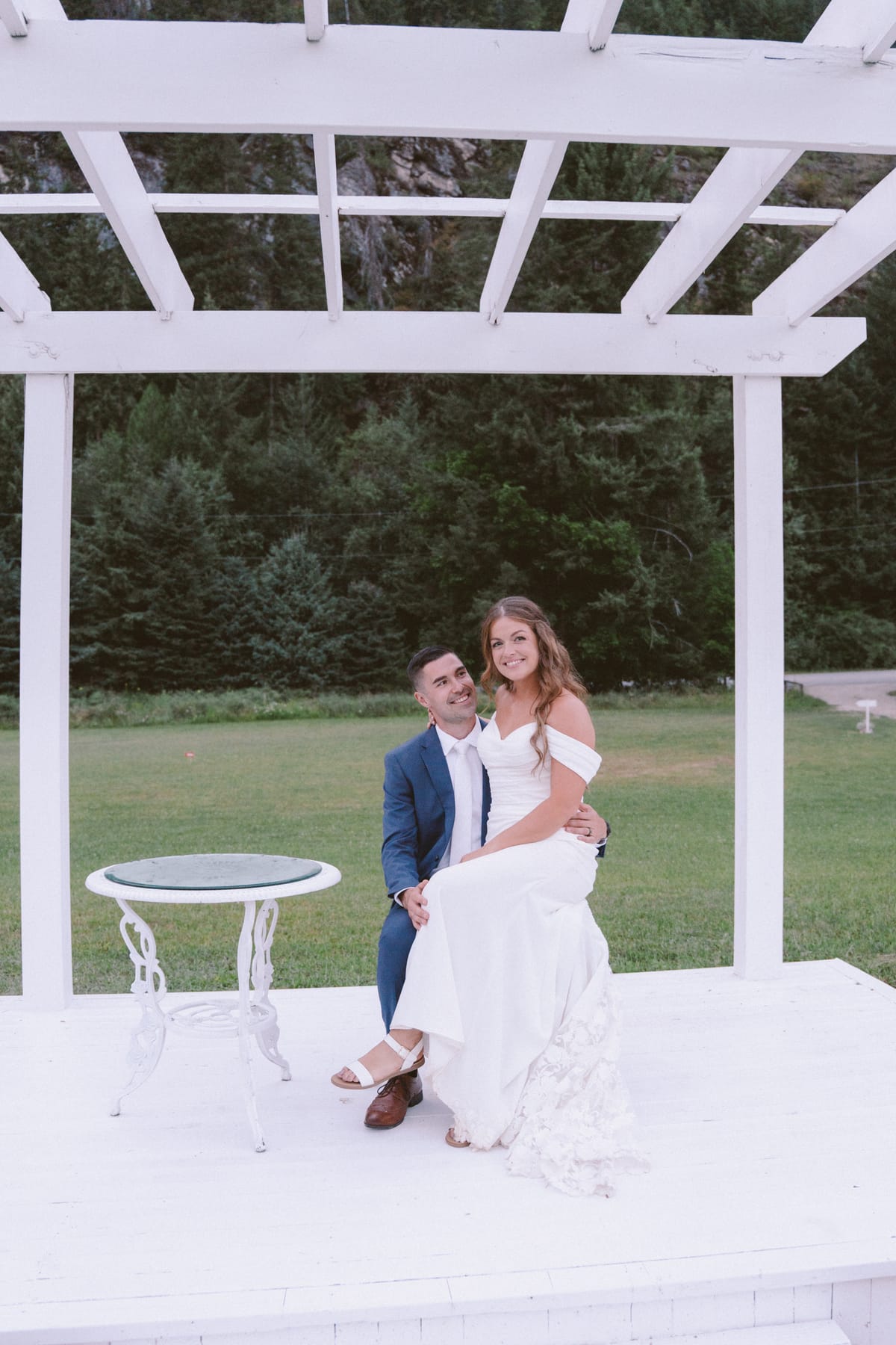 Kendra sitting on Rory's knee in the white gazebo at dusk