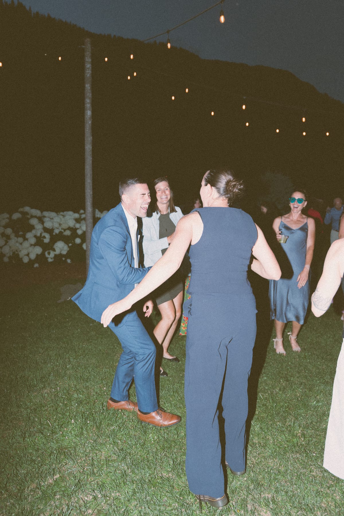 Rory dancing with guests on the lawn under string lights at night