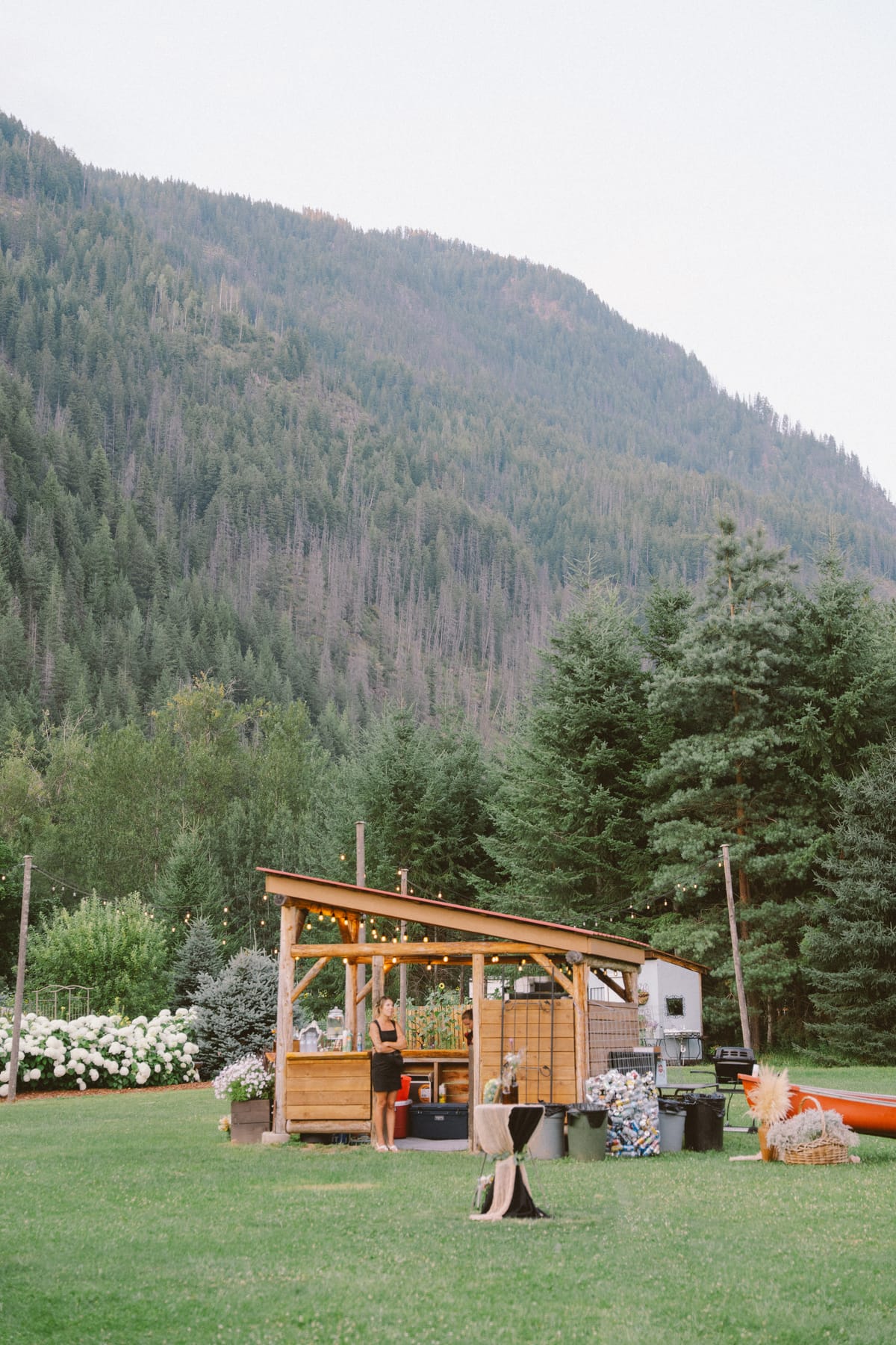 The timber bar pavilion strung with lights below the forested mountain at dusk