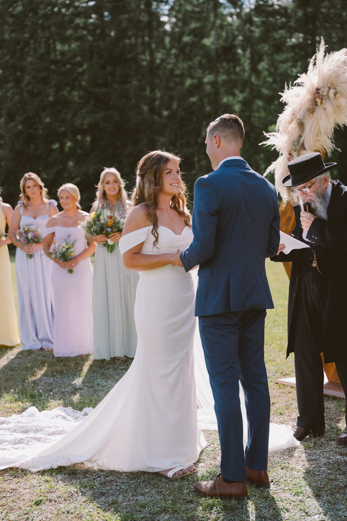 Kendra and Rory holding hands during their vows as the top-hatted officiant reads