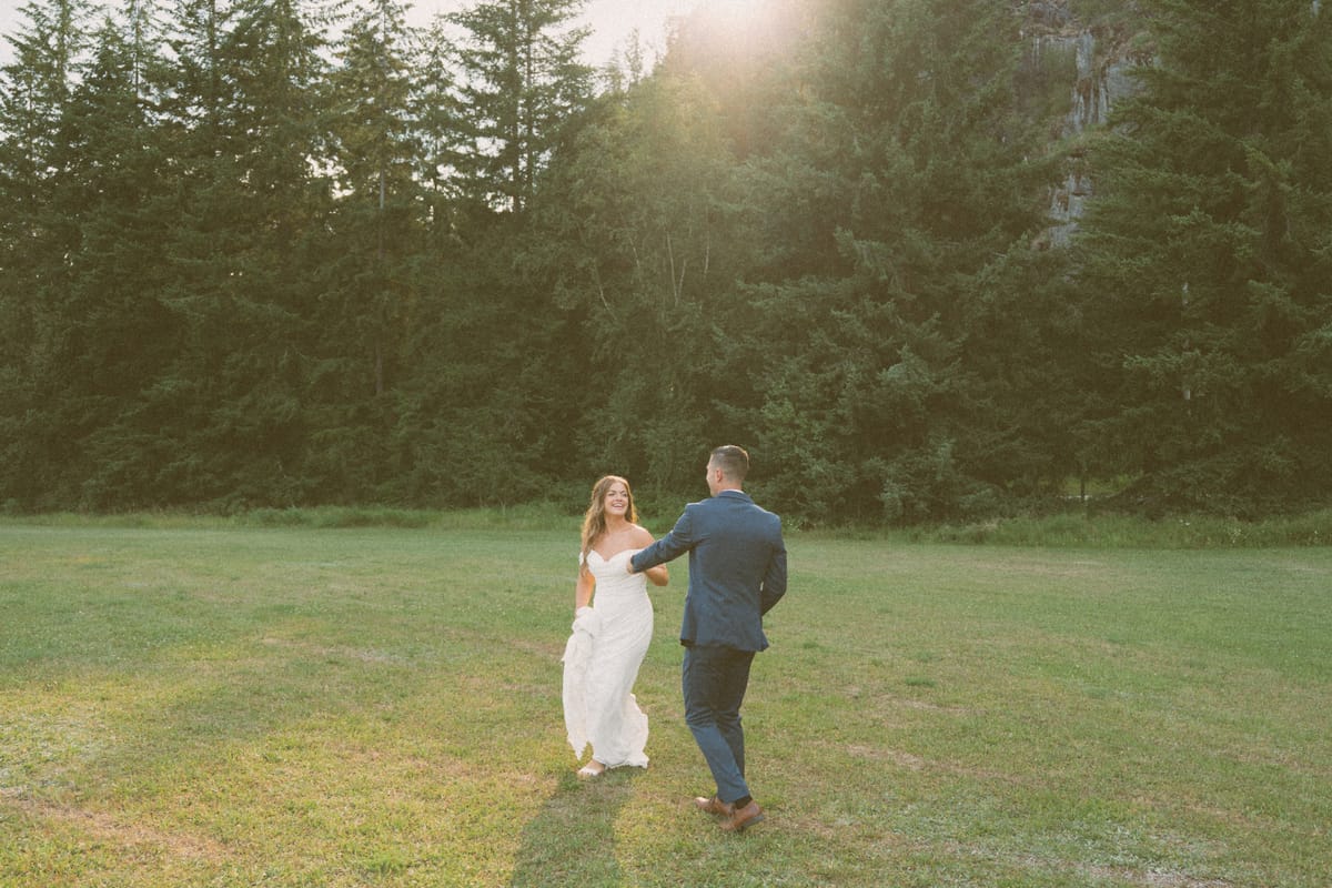 Kendra and Rory walking away hand in hand across the meadow into the sun