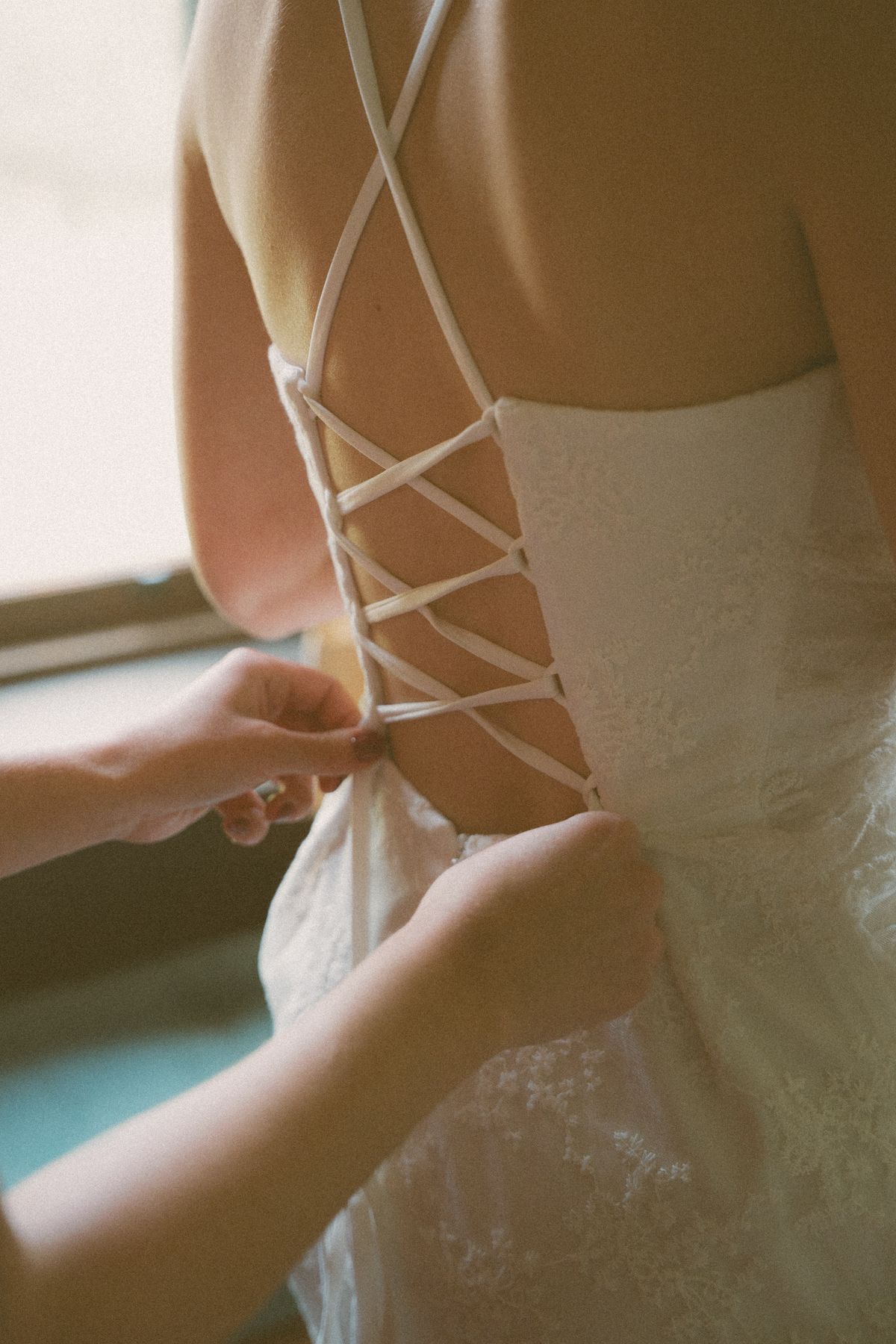 Detail of the bride's lace-up corset gown being tied