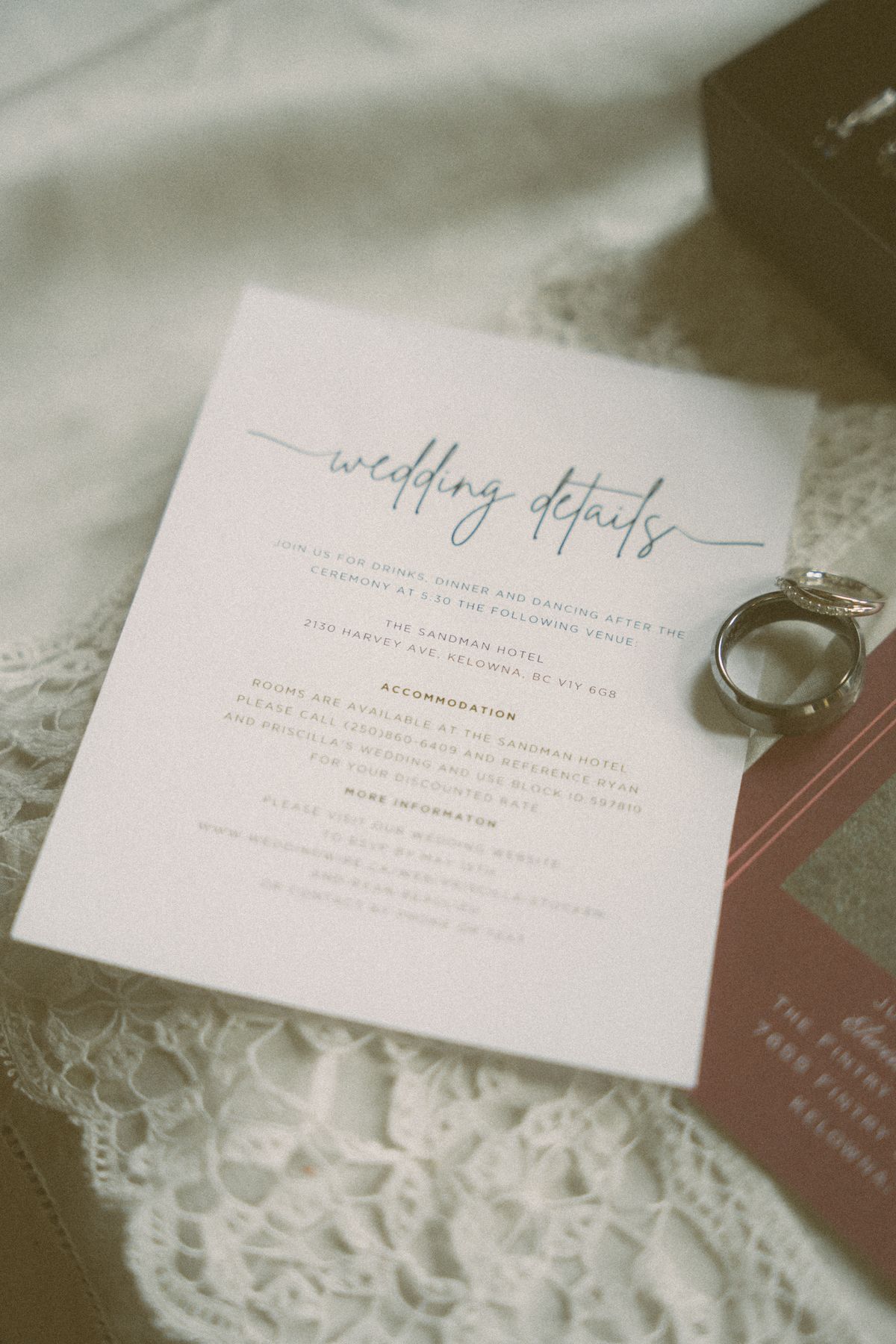 The wedding invitation and rings styled on lace