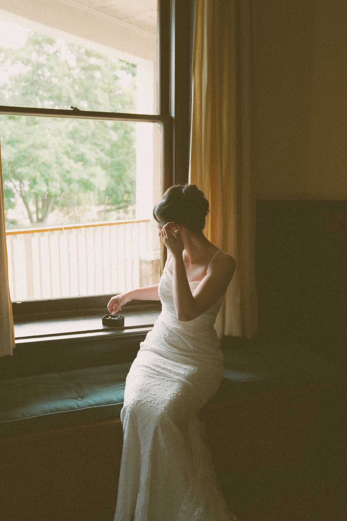 Bride seated by the manor window in her gown, looking out