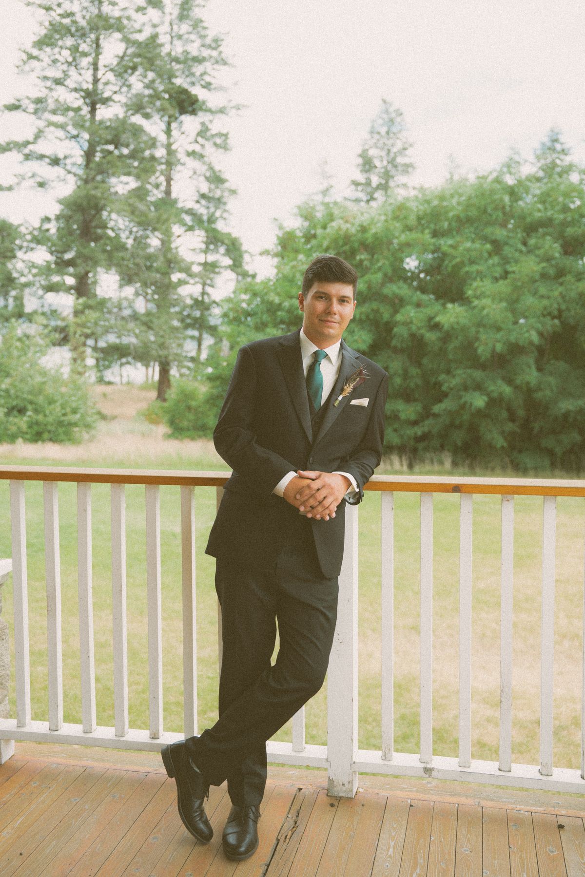 Groom leaning on the white verandah railing at Fintry Manor House