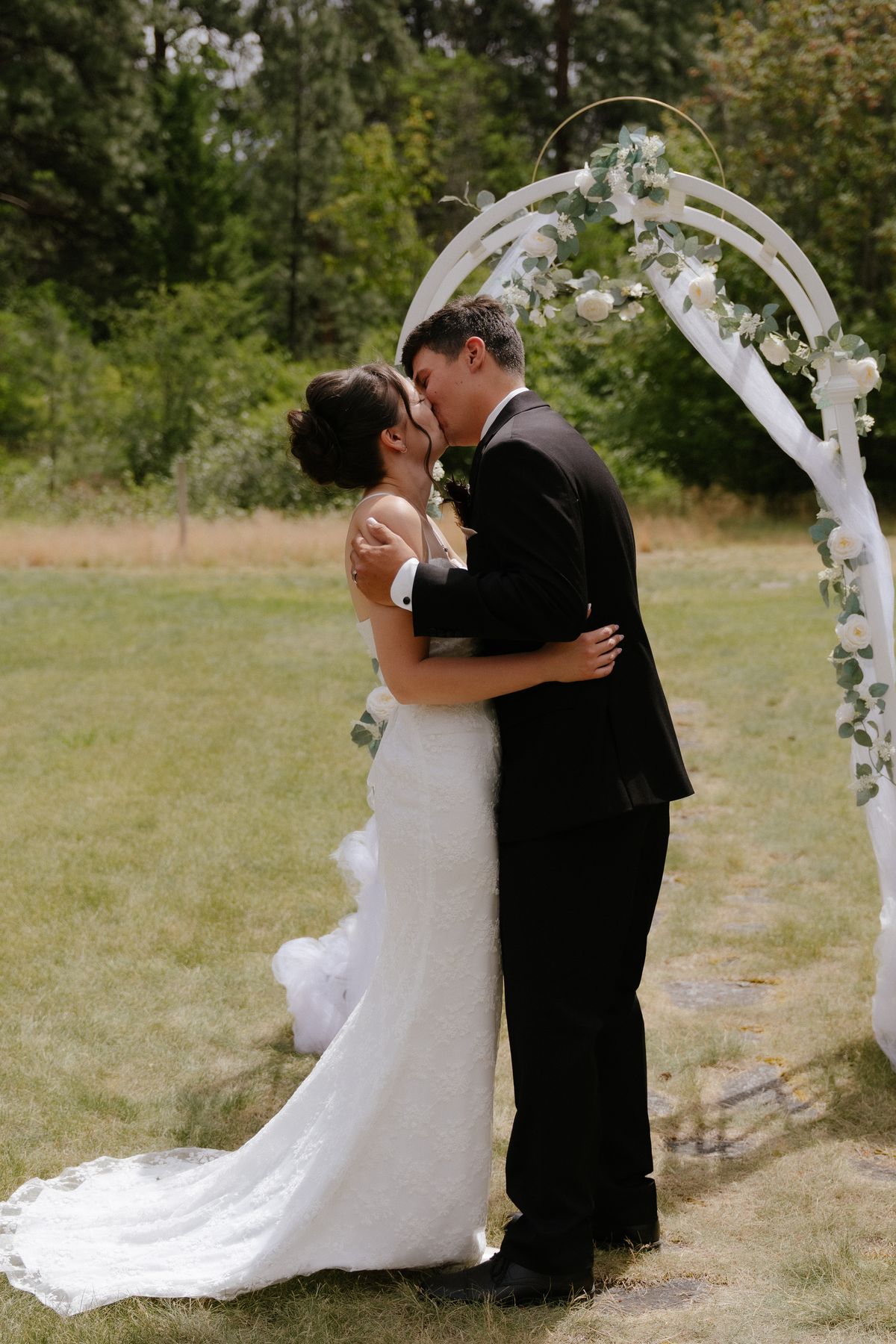Priscilla and Ryan's first kiss under the floral archway