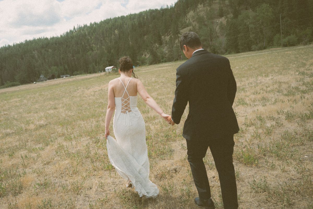 The couple walking hand in hand through the golden field at Fintry