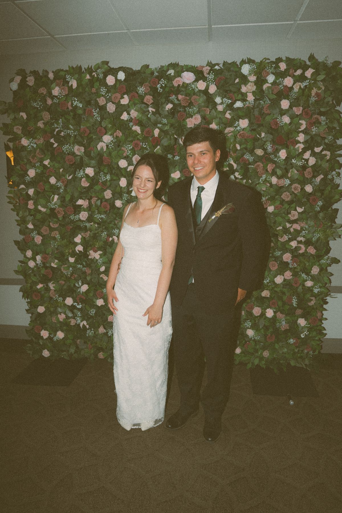 The couple in front of a rose flower wall backdrop
