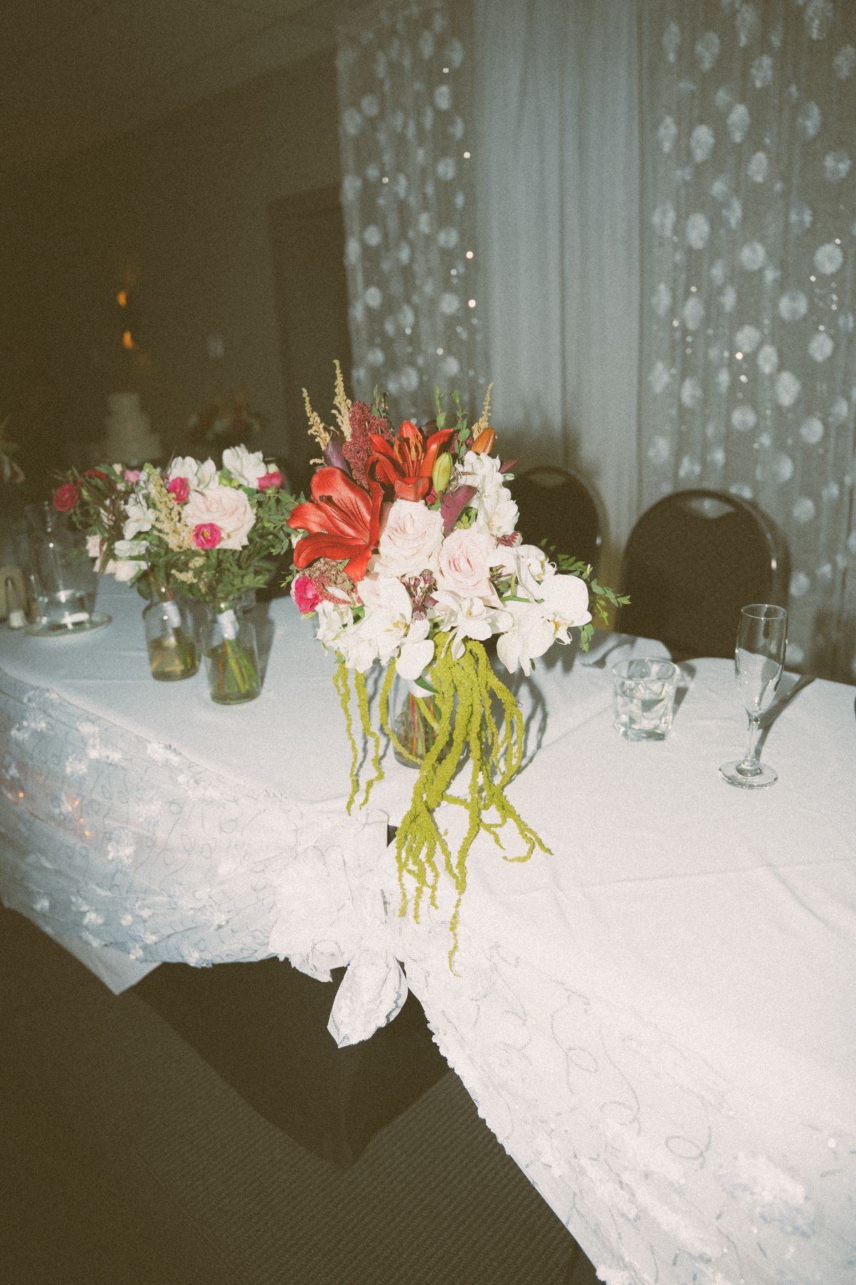 Detail of the head-table florals in reds and trailing amaranth
