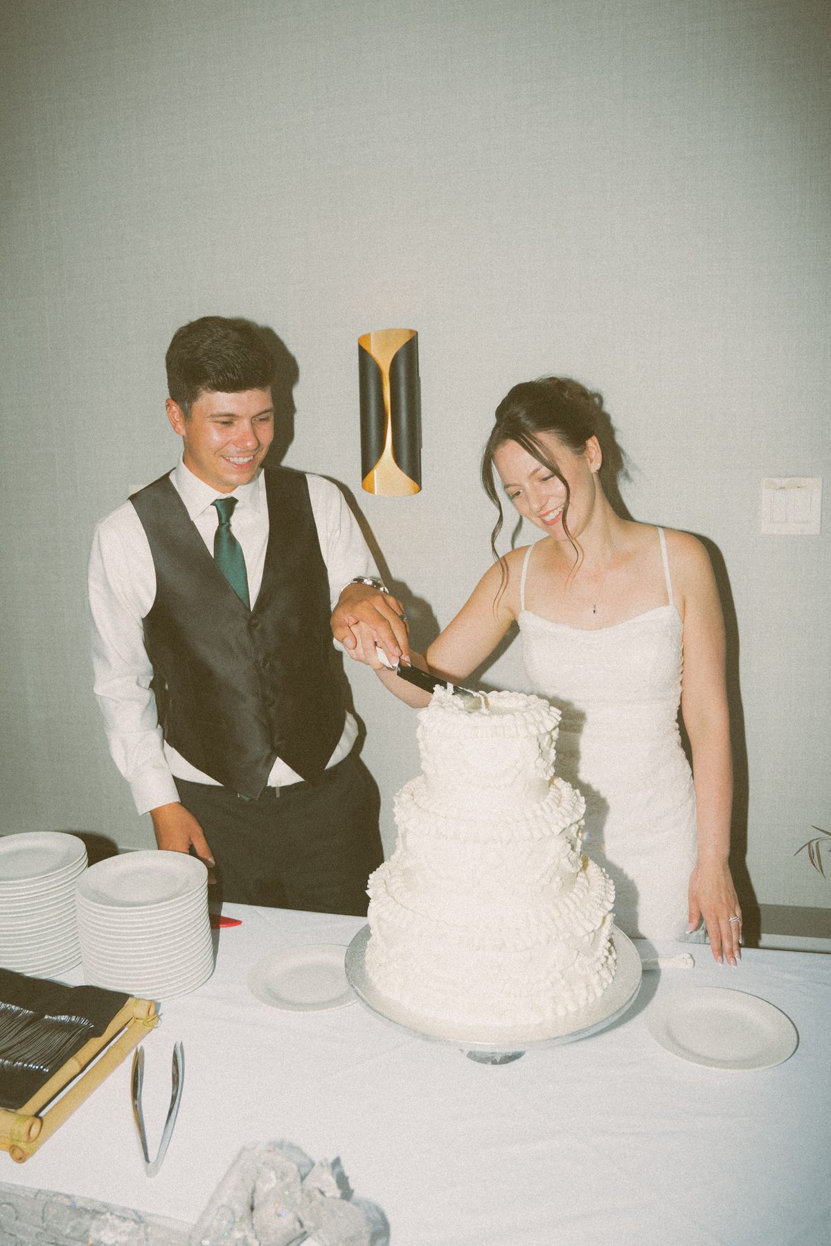 Bride and groom cutting their tiered cake at the reception