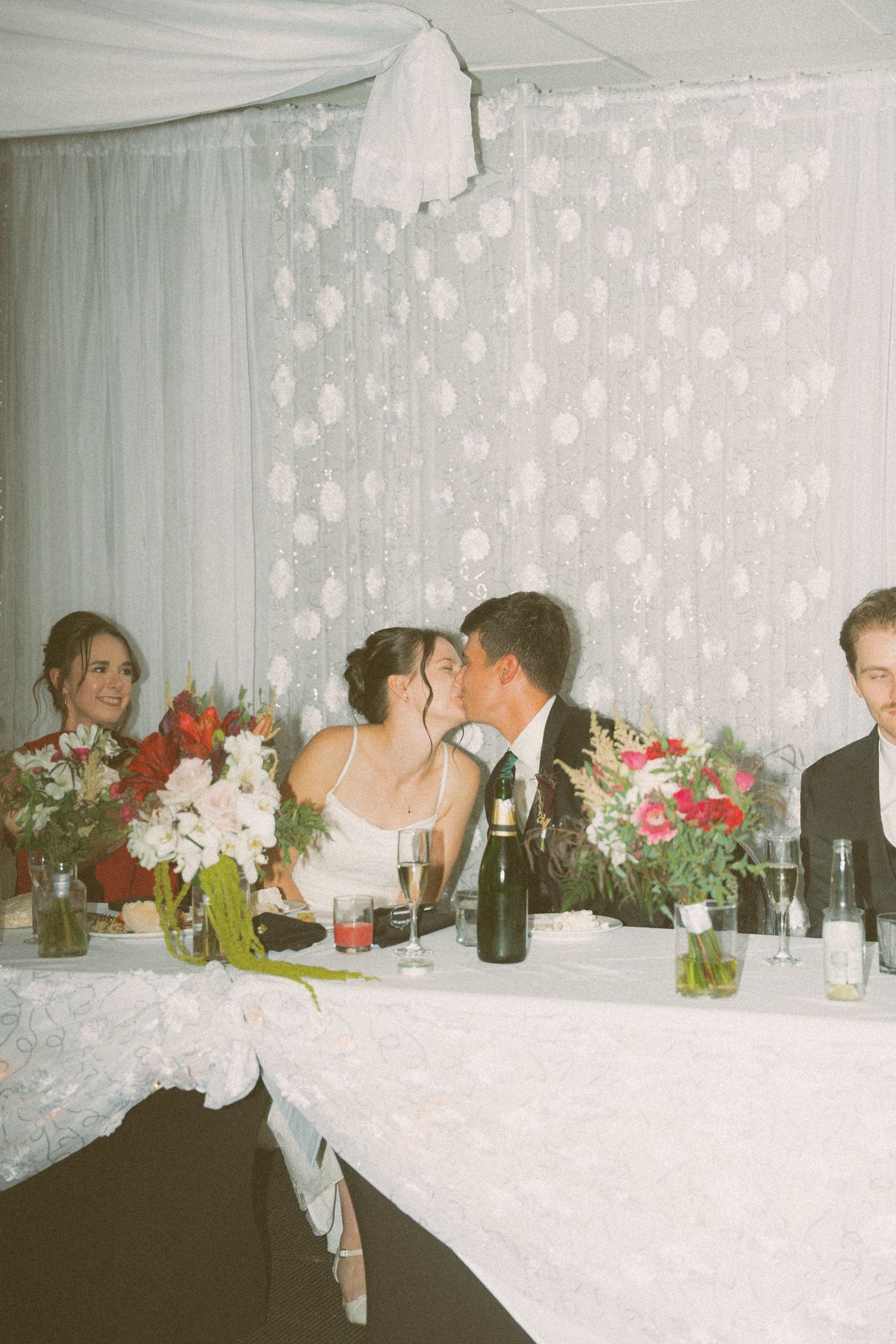 The couple sharing a kiss at the head table during dinner