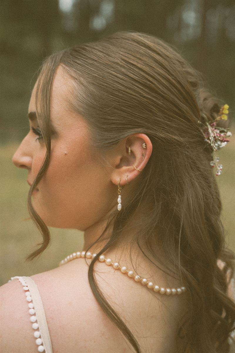 Detail of the bride's pearl necklace, gold earrings and the dried blooms tucked into her hair