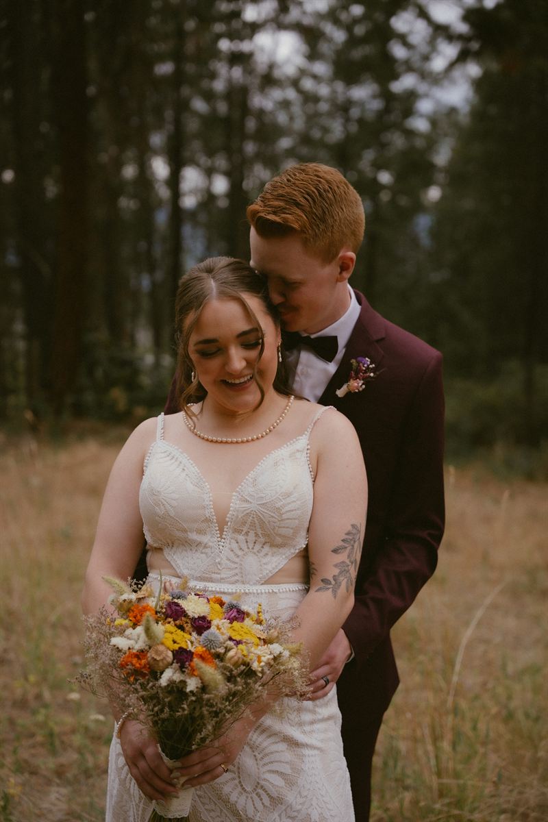 Groom leaning in close as the bride laughs, ponderosa pines rising behind them