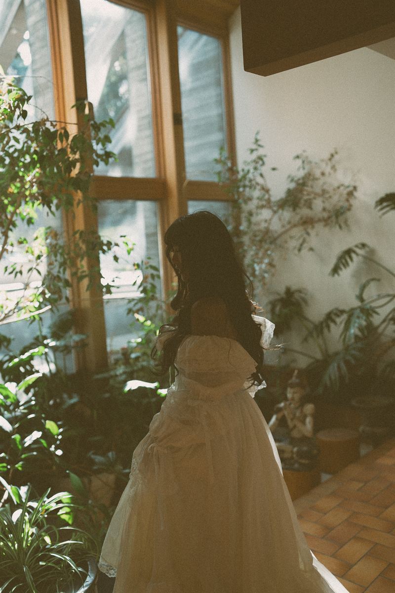 Bride in a vintage tulle gown turning through a bright, plant-filled sunroom