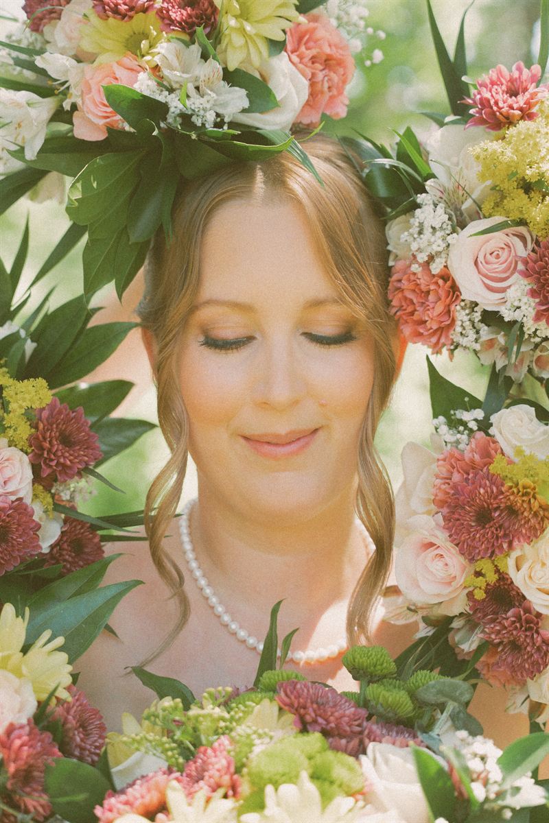 Bride framed by a hanging floral garland before her Kelowna ceremony