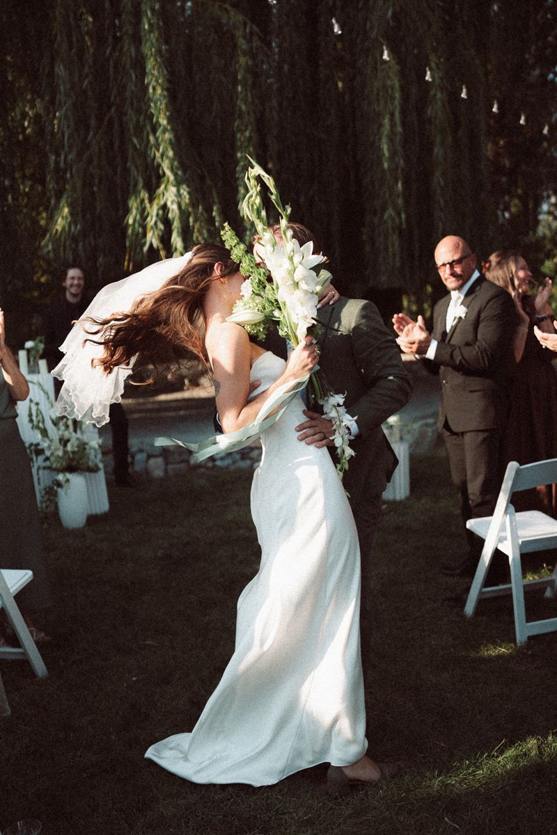 Recessional kiss under a willow tree at a Kelowna wedding
