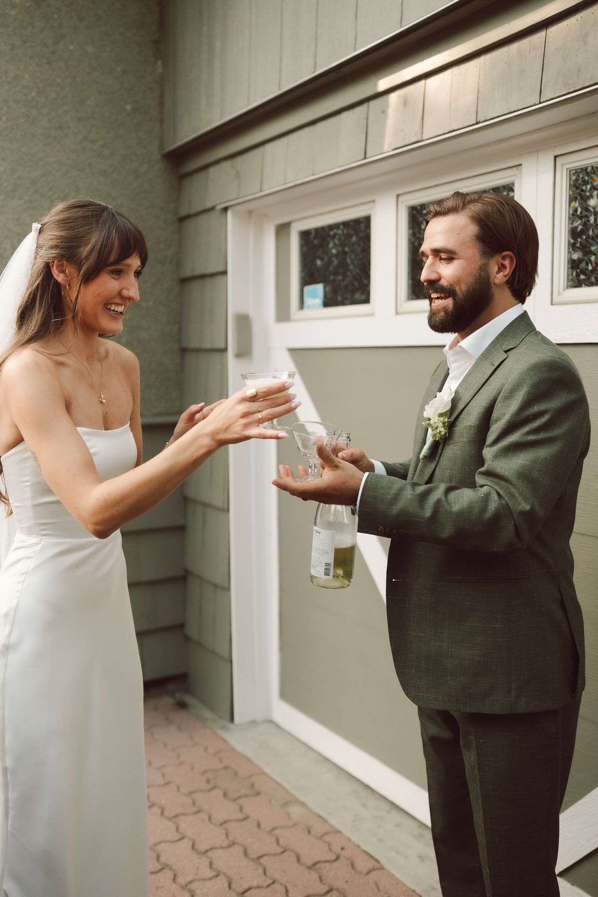 The couple by the house as the bride reaches out to the groom
