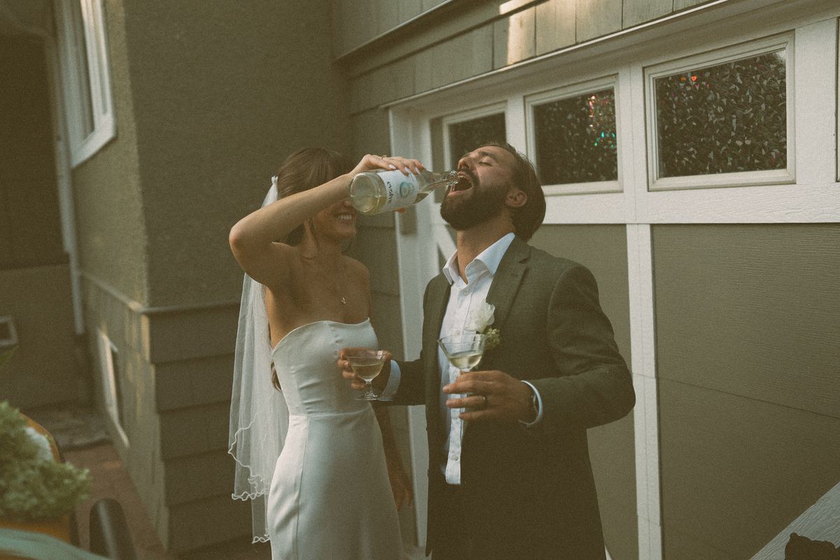 Groom celebrating with a drink beside the bride