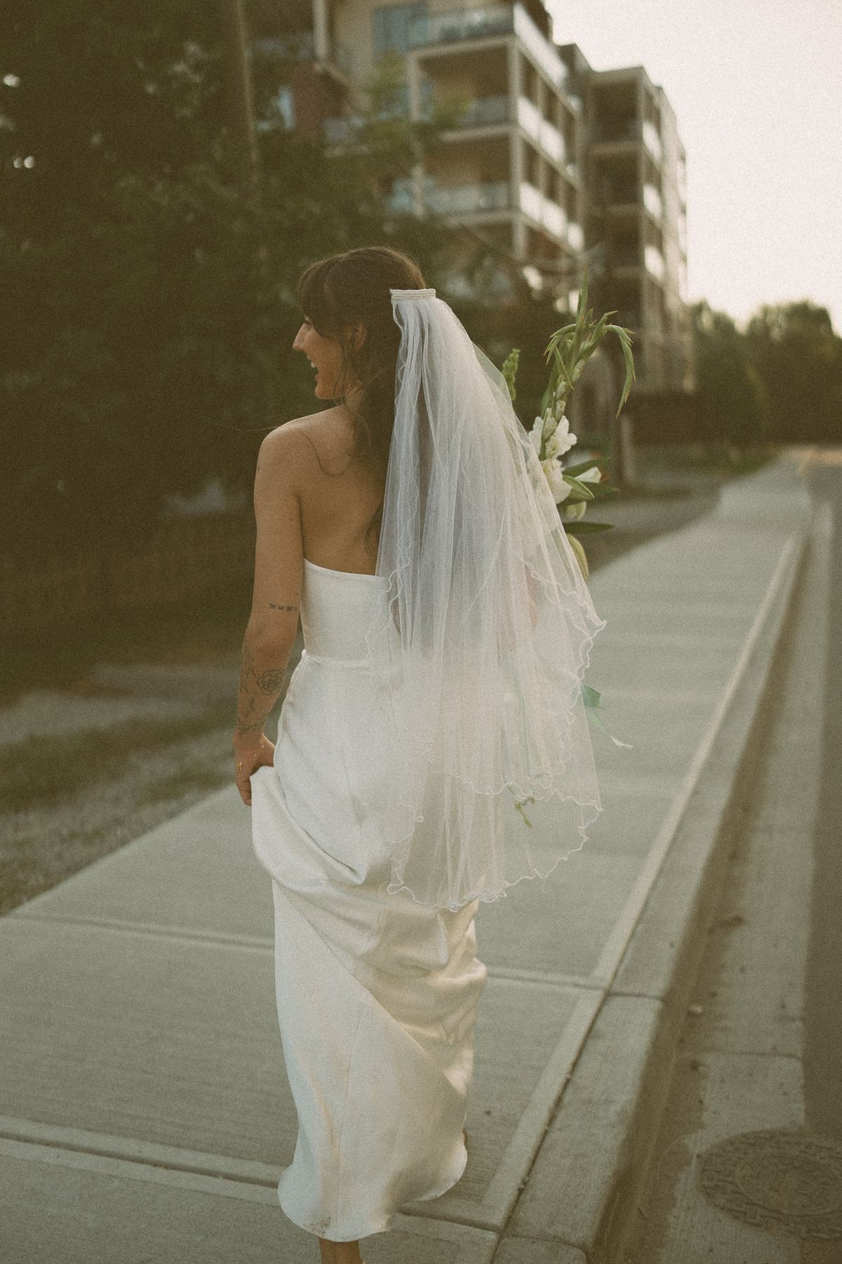 The bride from behind, veil trailing along the path