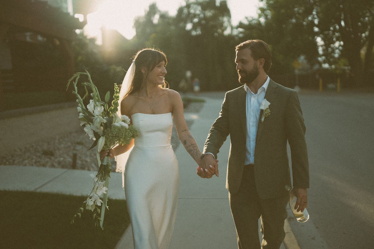Bride and groom walking hand in hand at sunset