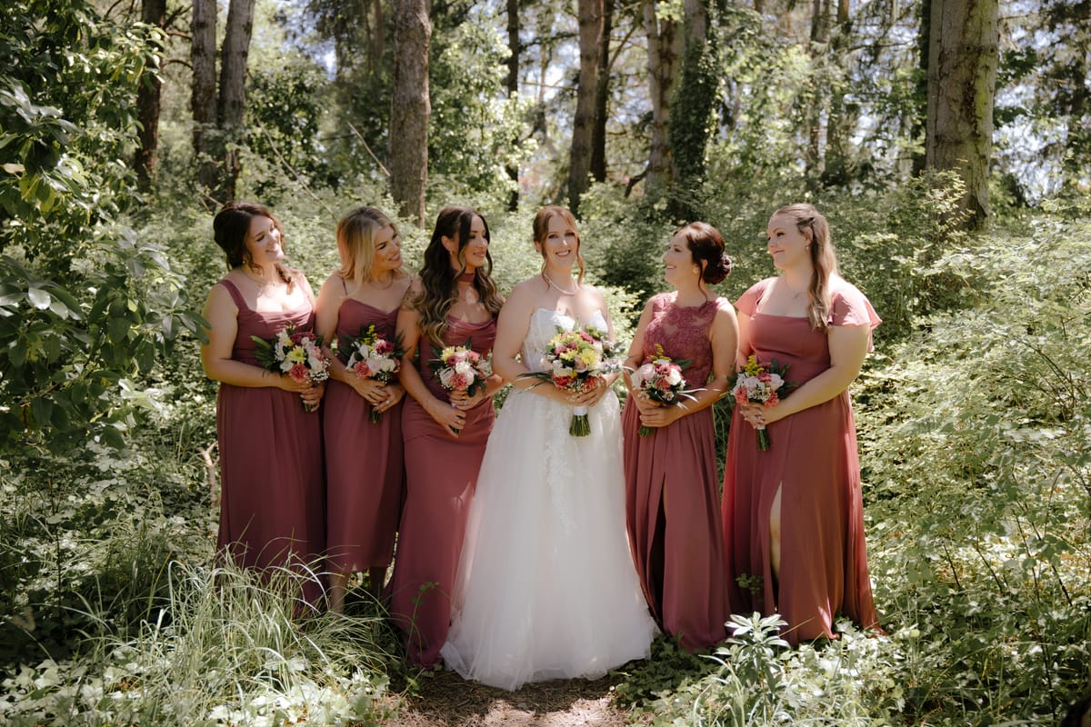 Charlotte with her bridesmaids in dusty rose among the coastal forest