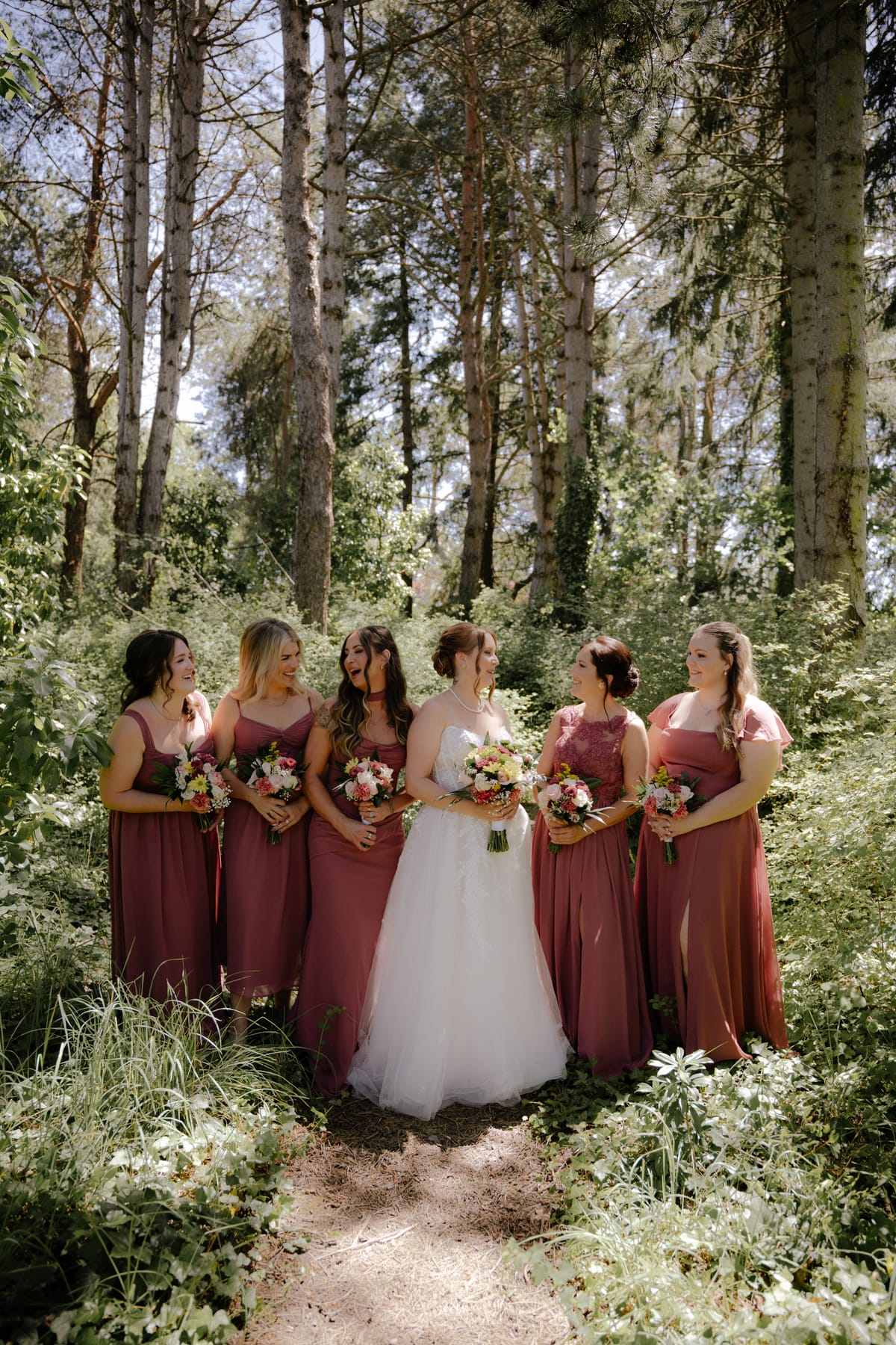 Charlotte and her bridesmaids gathered on a sunlit forest path