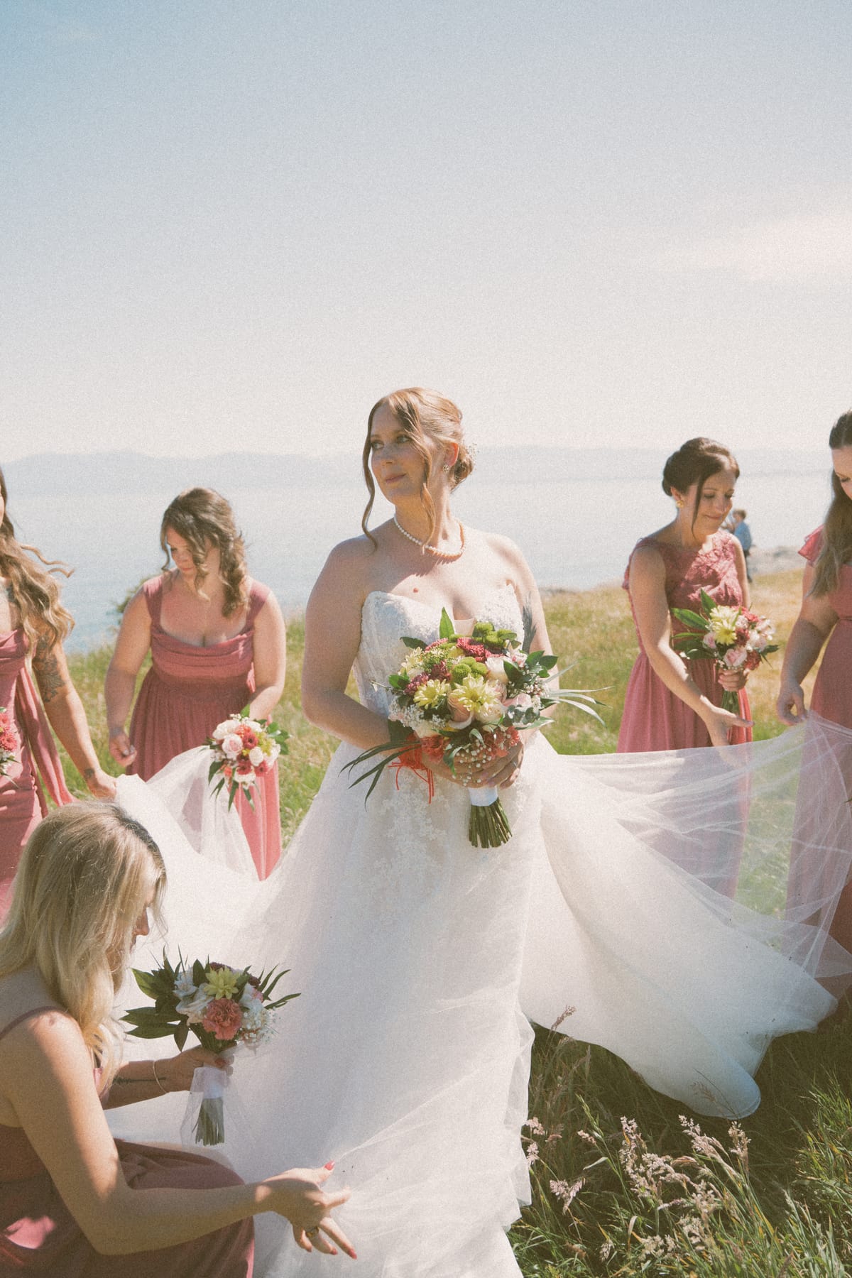 Charlotte and her bridesmaids carrying her train along the oceanfront bluff