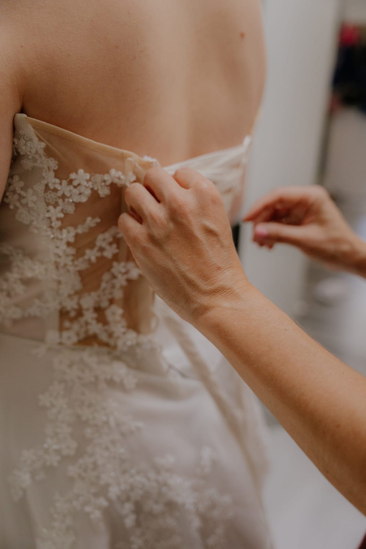 Buttoning the back of Charlotte's floral lace gown as she gets ready